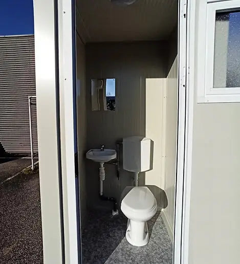 Cabine sanitária com sanita e lavatório.